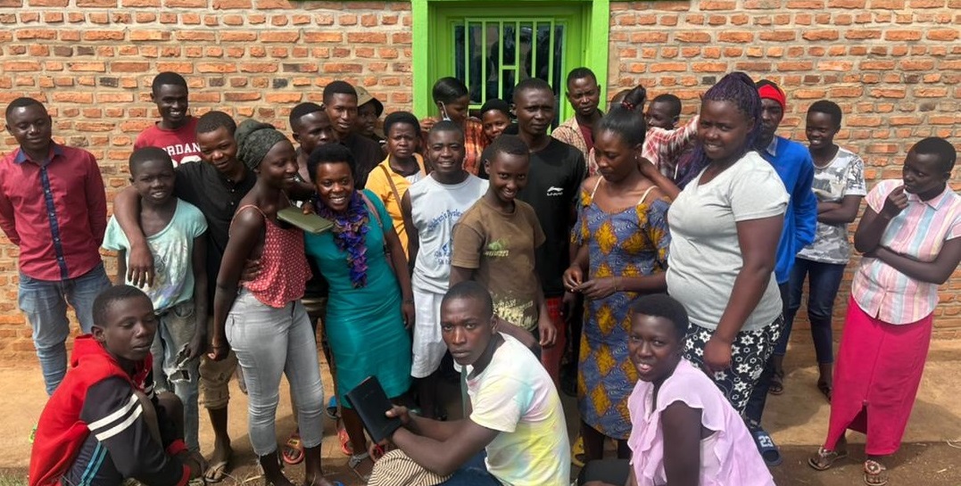 A group of Rwandan teenagers pose in front of a church